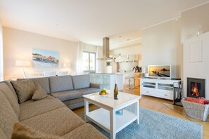 Un salon moderne avec un canapé gris, une table basse blanche, un téléviseur et une cheminée.