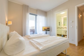Une chambre d’hôtel avec un lit, une télévision, une salle de bain avec un miroir et une vue sur l’extérieur.