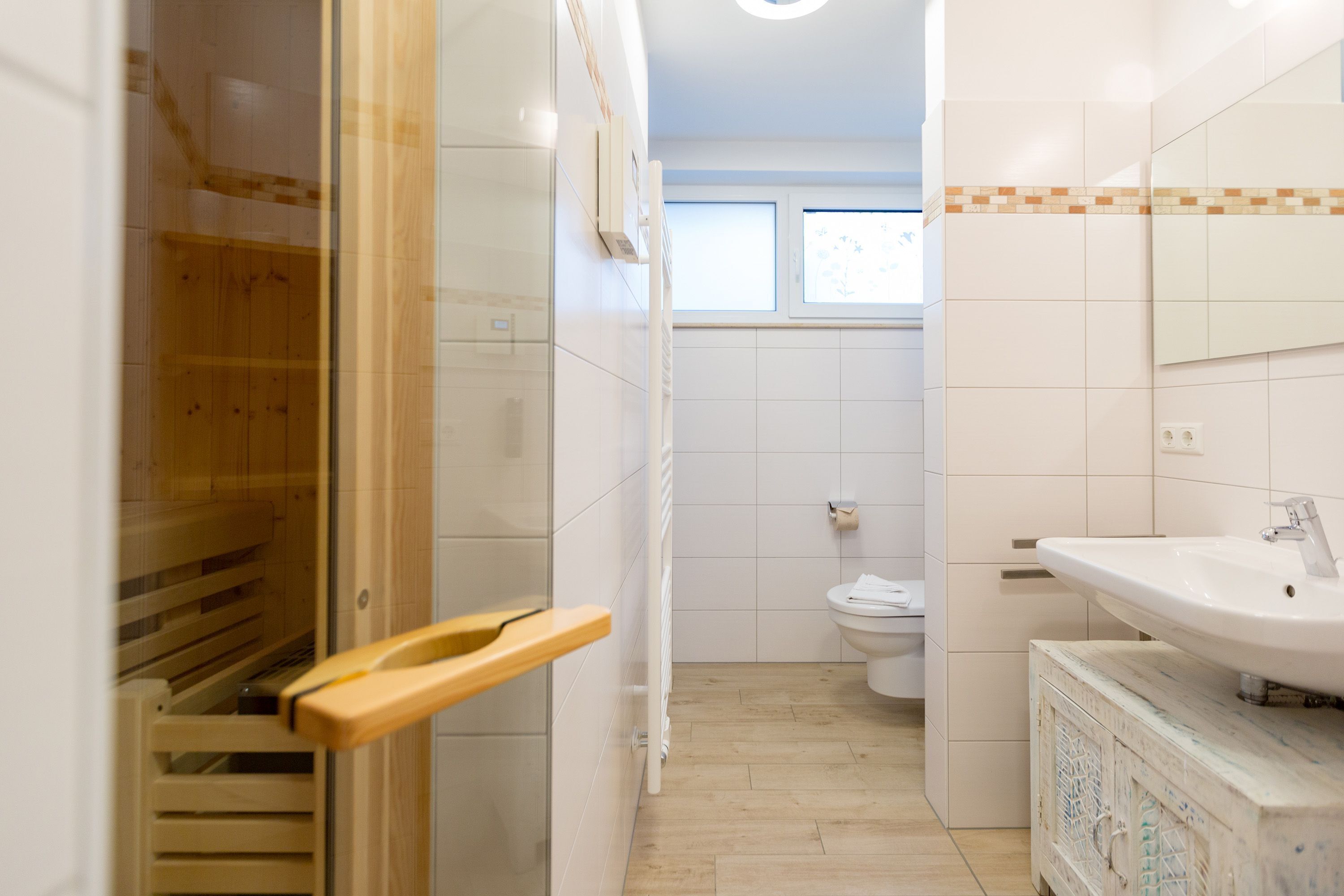 A bathroom with a wooden shower enclosure, a white sink, and a toilet.