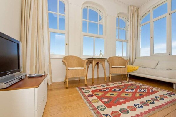 Un salon comprenant un téléviseur, un canapé, une table basse et un tapis à motifs.