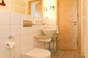Une salle de bain équipée de toilettes, d’un lavabo et d’un porte-serviettes.