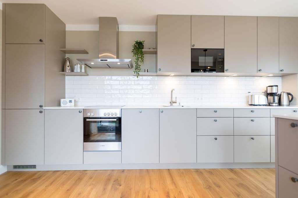 Een moderne keuken met lichte kastjes, een roestvrijstalen oven, een magnetron en een spoelbak.