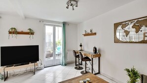 Un salon moderne avec un téléviseur à écran plat, une table à manger en bois, un tabouret de bar et une œuvre d’art représentant un globe terrestre accrochée au mur.