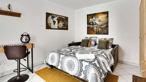 Une chambre à coucher avec un lit, un bureau et deux tableaux accrochés au mur.