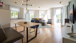 A modern kitchen with a dining table, a sofa, and a TV.