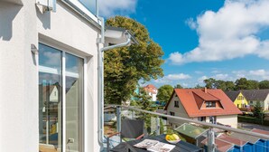 A balcony with a table, chairs, and a bowl of fruit.