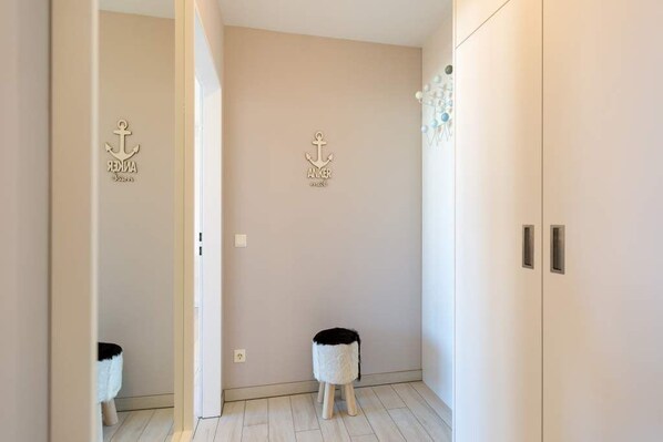 A hallway with a light-colored wall, two small stools, and a wardrobe.