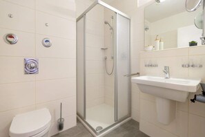 A modern bathroom with a glass-enclosed shower, a white sink, and a toilet. - Seehof Bansin, App. 1.23 (Heringsdorf)