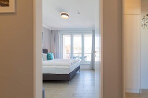 A bedroom with a bed, a window, and a door.