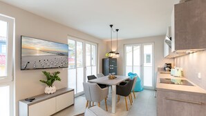 Una cucina moderna con zona pranzo, ampie finestre e una televisione a schermo piatto appesa al muro.