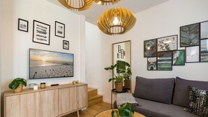 A modern living room with a large flat-screen TV, a grey sofa, a round coffee table, and a wooden cabinet. - Quartier am Kurpark, App. 12 Garden house (Heringsdorf)