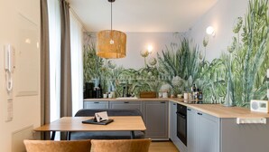A modern kitchen with grey cabinets, a wooden countertop, and a dining area with two chairs. - Quartier am Kurpark, App. 12 Garden house (Heringsdorf)