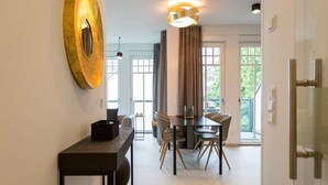 A modern dining area with a table and chairs, a wall-mounted light fixture, and a door leading to another room.