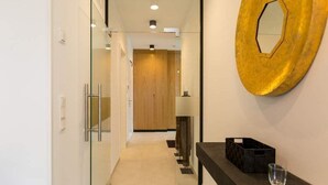 A modern hallway with a glass door, a wooden door, and a black countertop with a glass.