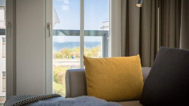 A modern living room with a large window, a sofa, and a view of the outdoors.