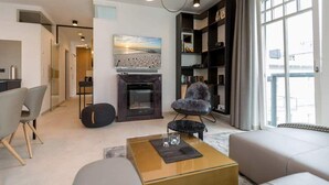 A modern living room with a fireplace, a sofa, a coffee table, and a bookshelf.