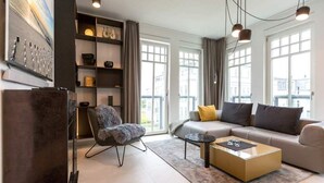 A modern living room with a sofa, armchair, coffee table, and a bookshelf.