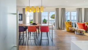 Ein modernes Wohnzimmer mit Essbereich, großen Fenstern und Blick ins Freie.