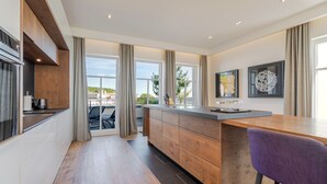 Eine moderne Küche mit einer Holztheke, großen Fenstern und Blick ins Freie.