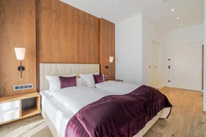Une chambre moderne avec un grand lit, des murs recouverts de panneaux de bois, des lampes de chevet et une porte.