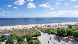 Eine Uferpromenade mit freiem Blick auf das Meer, ein Sandstrand und ein Weg zu Badeeinrichtungen.