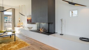 Ein modernes Wohnzimmer mit Kamin, Glastisch und Sofa.