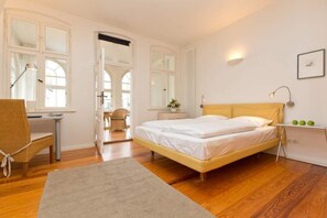 Une chambre à coucher avec un lit, un bureau, une chaise et une fenêtre.