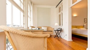 A cozy room with a wicker chair, a small table, and a bed. - Villa Astrid, T1 Cologne (Heringsdorf)