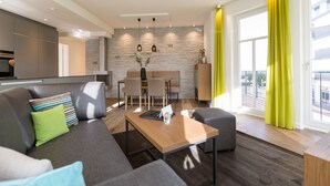 A modern living room with a sofa, a coffee table, and a dining area with chairs and a table. - Beachhouse Bansin, app. 14 (Heringsdorf)