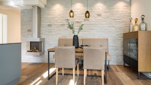A modern dining area with a stone wall, wooden flooring, and pendant lighting. - Beachhouse Bansin, app. 14 (Heringsdorf)
