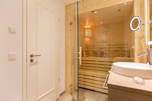 A modern bathroom with a glass door leading to a sauna area. - Beachhouse Bansin, app. 14 (Heringsdorf)