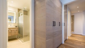 Ein modernes Badezimmer mit einer Duschkabine aus Glas, Holzschränken und einem hellen Boden.