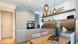 Eine moderne Küche mit einem Holztisch, integrierten Geräten und einer Pendelleuchte.