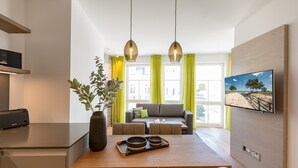 Eine moderne Küche mit Essbereich, einer Couch und einem an der Wand befestigten Fernseher.