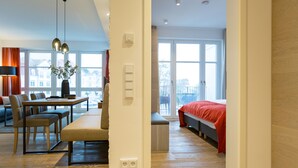 Een moderne woonkamer met een eethoek, grote ramen en een rood bed.