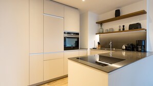 Een moderne keuken met witte kastjes, een roestvrijstalen spoelbak en een ingebouwde oven.