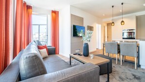 Ein modernes Wohnzimmer mit grauem Sofa, einem Couchtisch und einem Essbereich mit Stühlen und Tisch.