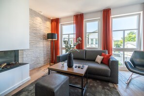 A modern living room with a stone accent wall, a sofa, a coffee table, and a black armchair. - Beachhouse Bansin, App. 24 (Heringsdorf)