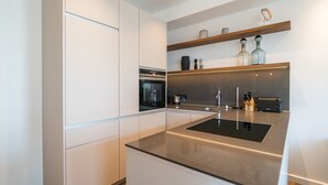 A modern kitchen with white cabinetry, a black countertop, and stainless steel appliances. - Beachhouse Bansin, App. 21 (Heringsdorf)