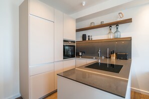 Uma cozinha moderna com armários brancos, bancada preta e eletrodomésticos de aço inoxidável.