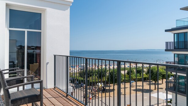 A balcony with wicker chairs, a view of the sea, and a beach with umbrellas. - Beachhouse Bansin, App. 21 (Heringsdorf)