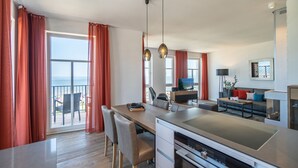 A modern kitchen with a dining area, large windows, and a view of the sea. - Beachhouse Bansin, App. 19 (Heringsdorf)