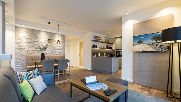 A modern living room with a sofa, coffee table, and a dining area with chairs. - Beachhouse Bansin, App. 18 (Heringsdorf)