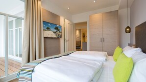 A hotel room with a large bed, a view of the outdoors, and a wooden wardrobe. - Beachhouse Bansin, App. 18 (Heringsdorf)