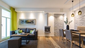 A modern living room with a sofa, ottoman, and dining area. - Beachhouse Bansin, App. 18 (Heringsdorf)