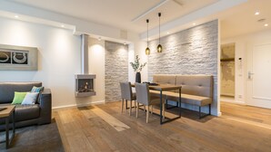 A modern living room with a fireplace, a sofa, a dining table with chairs, and a stone accent wall. - Beachhouse Bansin, App. 18 (Heringsdorf)