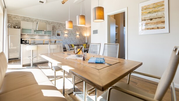 Een moderne keuken met een eethoek, een houten tafel en barstoelen.