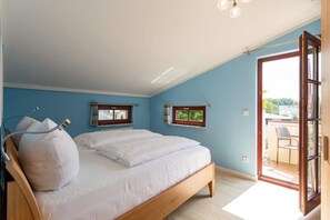 Quarto com uma cama, janela e porta que dá para uma varanda.