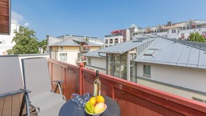 Een balkon met een tafel, stoelen en een fles wijn.