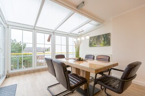 Een moderne vergaderruimte met een glazen tafel, lederen stoelen, een schilderij aan de muur en een uitzicht door grote ramen.